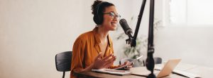 Woman recording a podcast on her laptop computer with headphones 